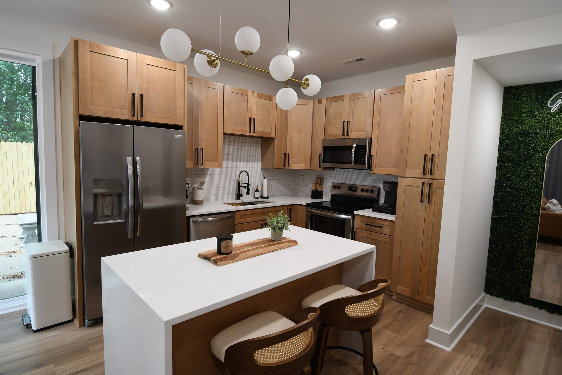 Kitchen with maple shaker cabinets, waterfall quartz island, and globe pendant lighting