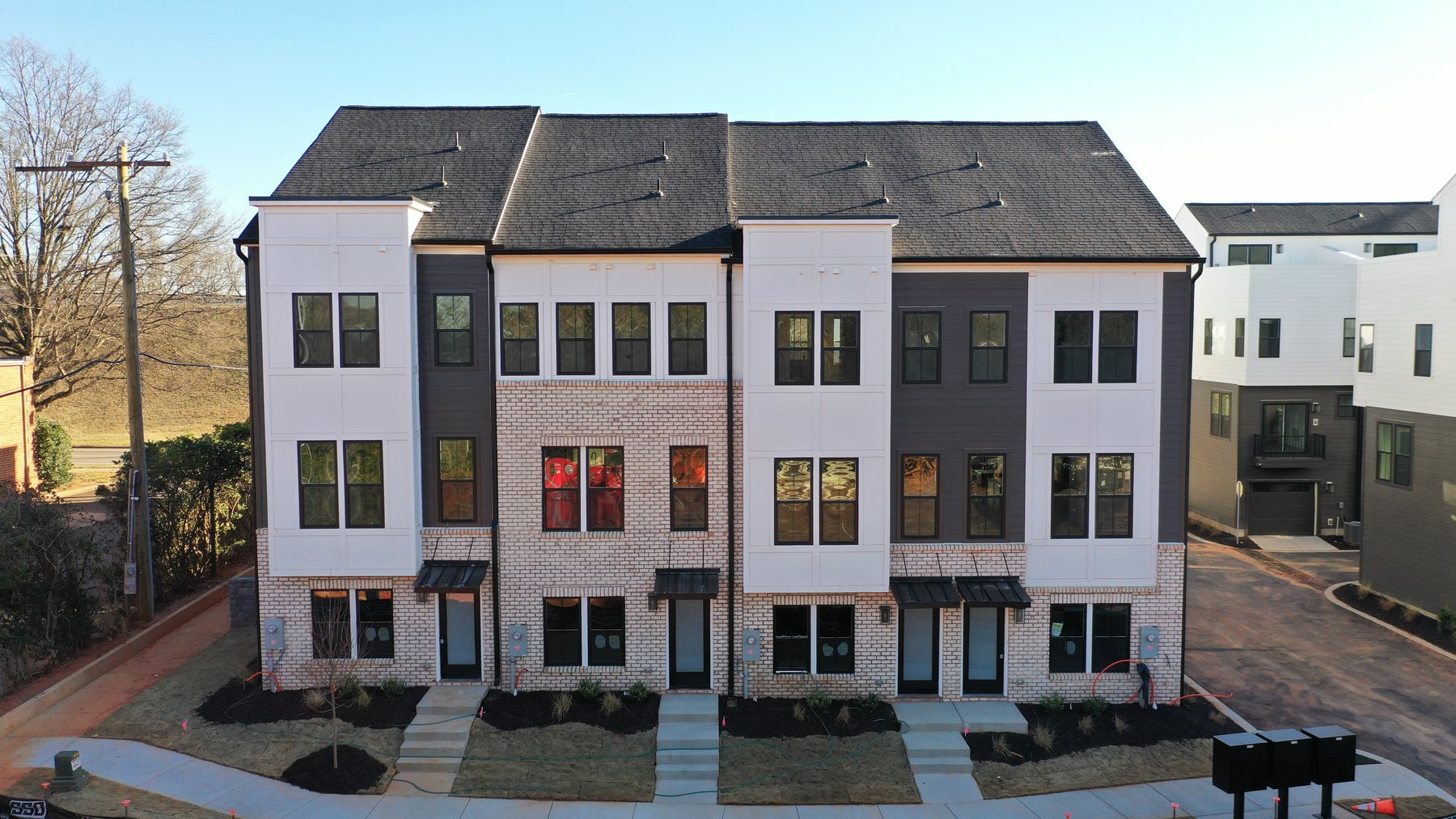Elevated exterior view of a new-construction townhome row with brick and board-and-batten facades